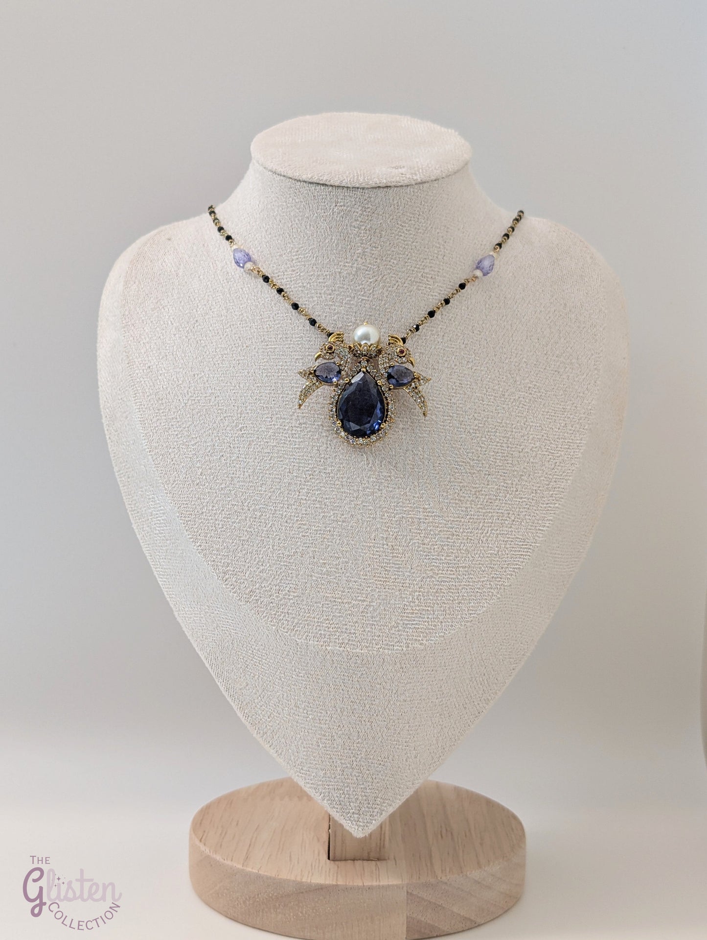 Black bead necklace with sapphire bird pendant, diamond accents, and white pearl — whimsical and elegant design perfect for festive wear.