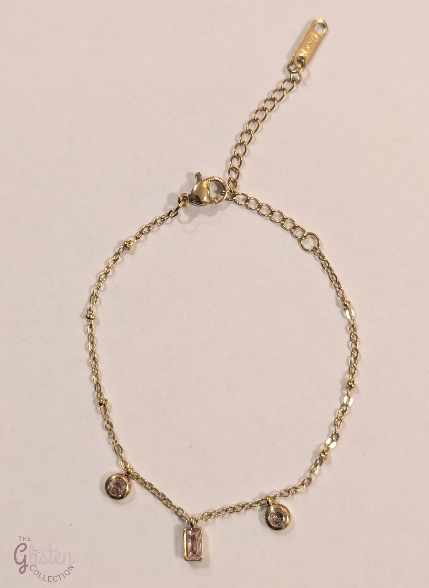 Pink charm geometric bracelet with circular and rectangular charms in pink, complemented by gold-plated links for a stylish and minimalist look.