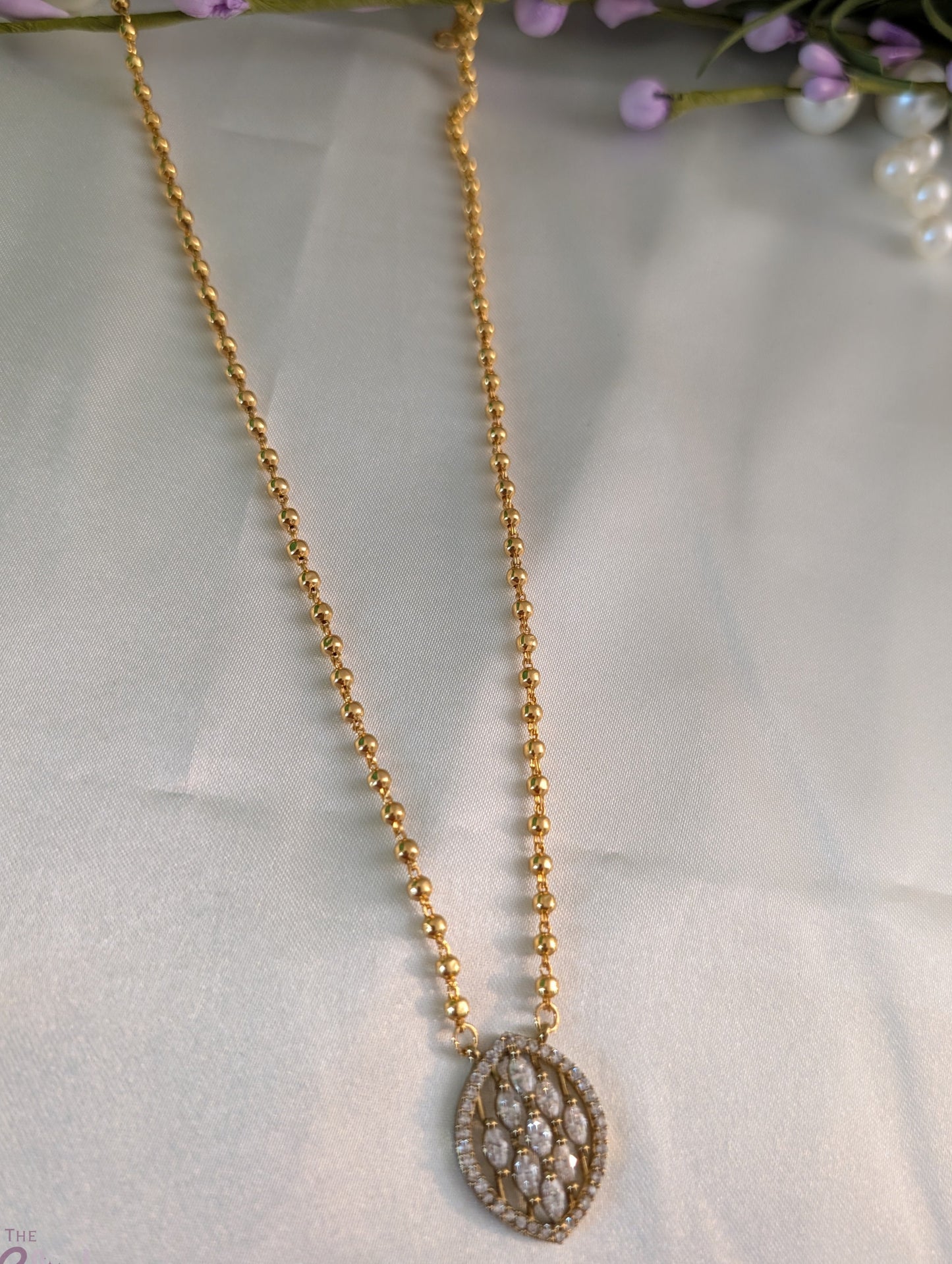 Gold-tone short necklace with gold balls and leaf-shaped pendant adorned with stones — simple, elegant daily wear jewellery.