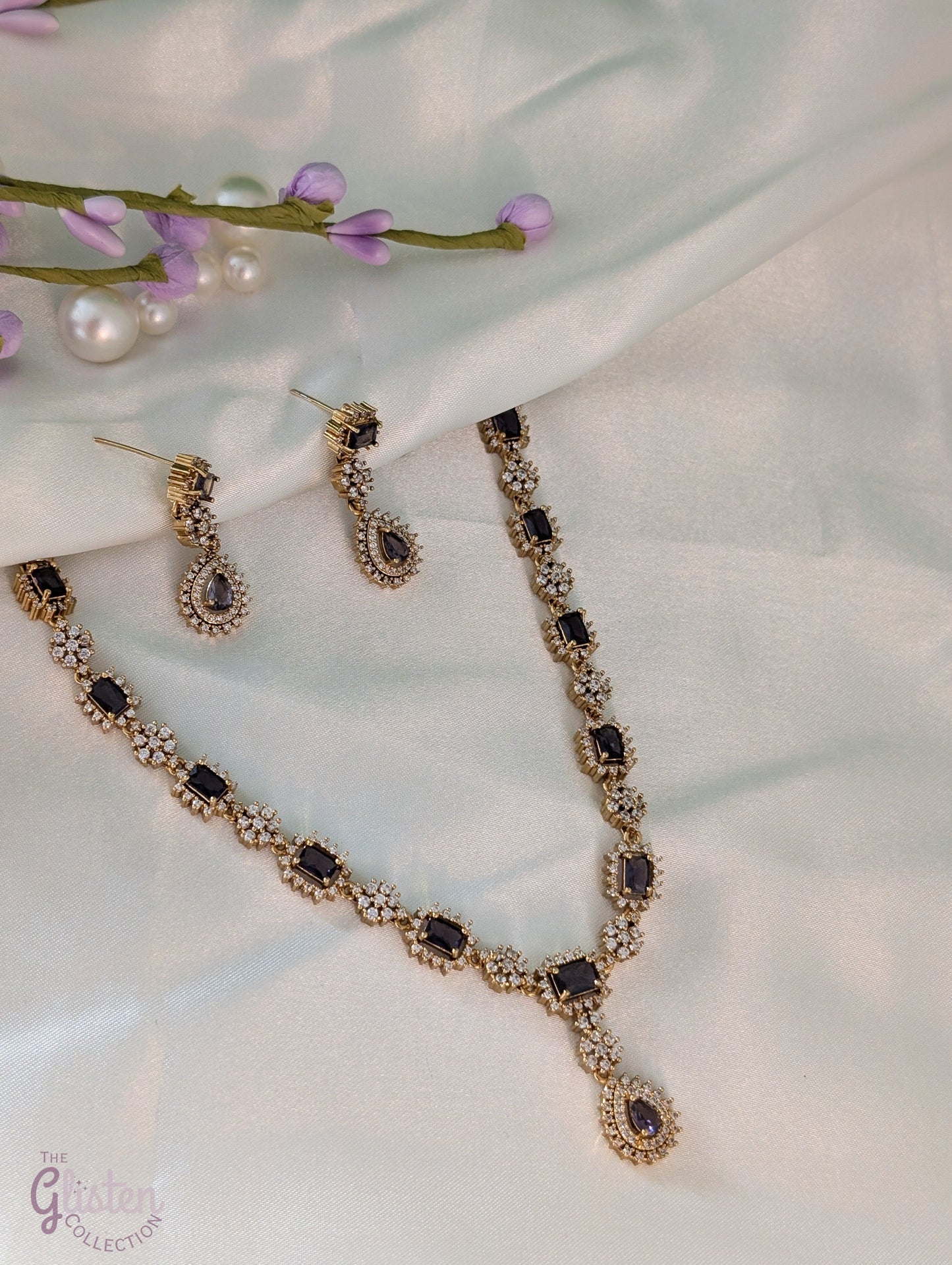 Gold-toned necklace and earrings set with deep purple drop stones, ideal for Indian attire, party dresses, and elegant everyday wear.