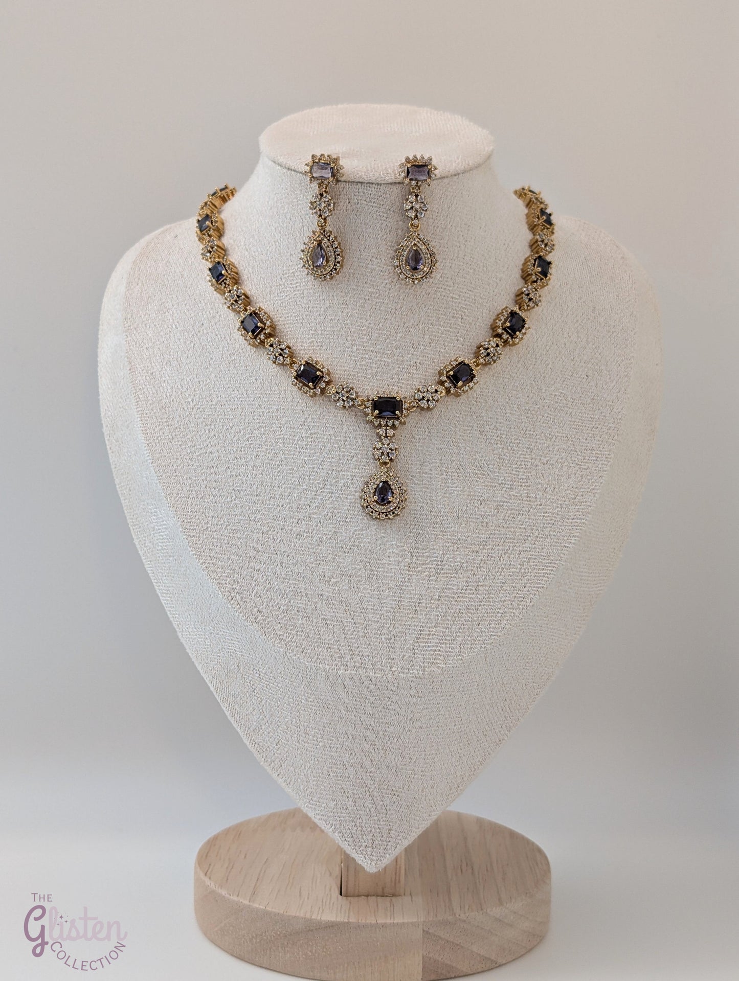 Gold-toned necklace and earrings set with deep purple drop stones, ideal for Indian attire, party dresses, and elegant everyday wear.