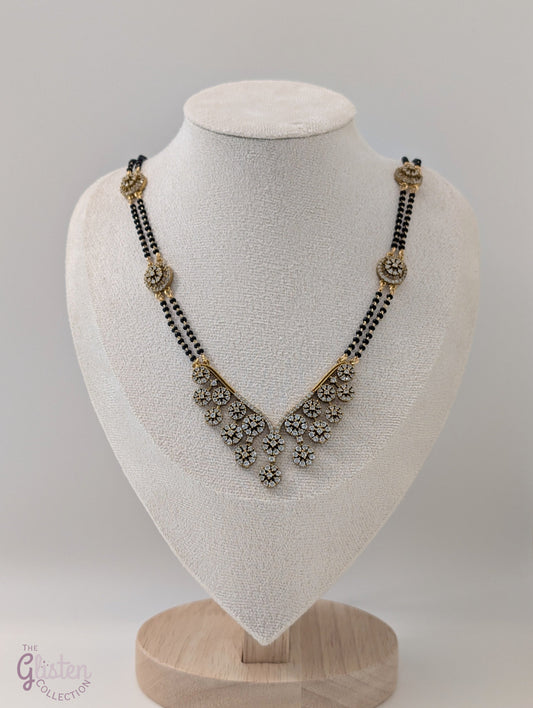 Long mangalsutra with black beads, V-shaped stone pendant, and round stone accents — ideal for modern traditional wear and daily elegance.