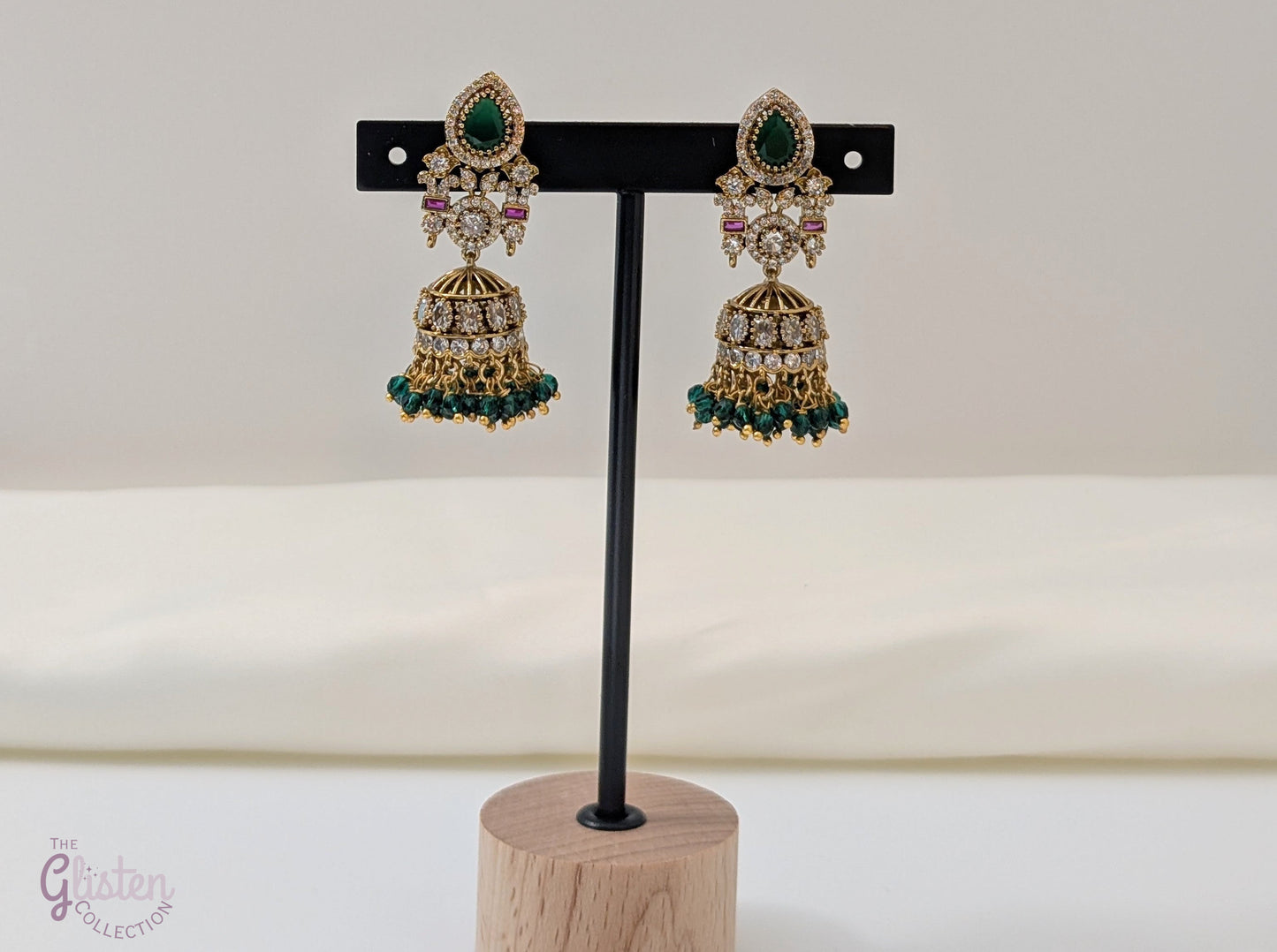 Emerald Flow Jhumkas with green stones, delicate accents, and green bead dangles — perfect for simple yet festive looks at parties and special occasions.