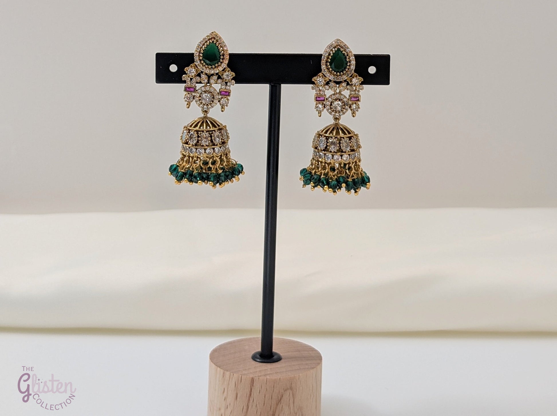 Emerald Flow Jhumkas with green stones, delicate accents, and green bead dangles — perfect for simple yet festive looks at parties and special occasions.