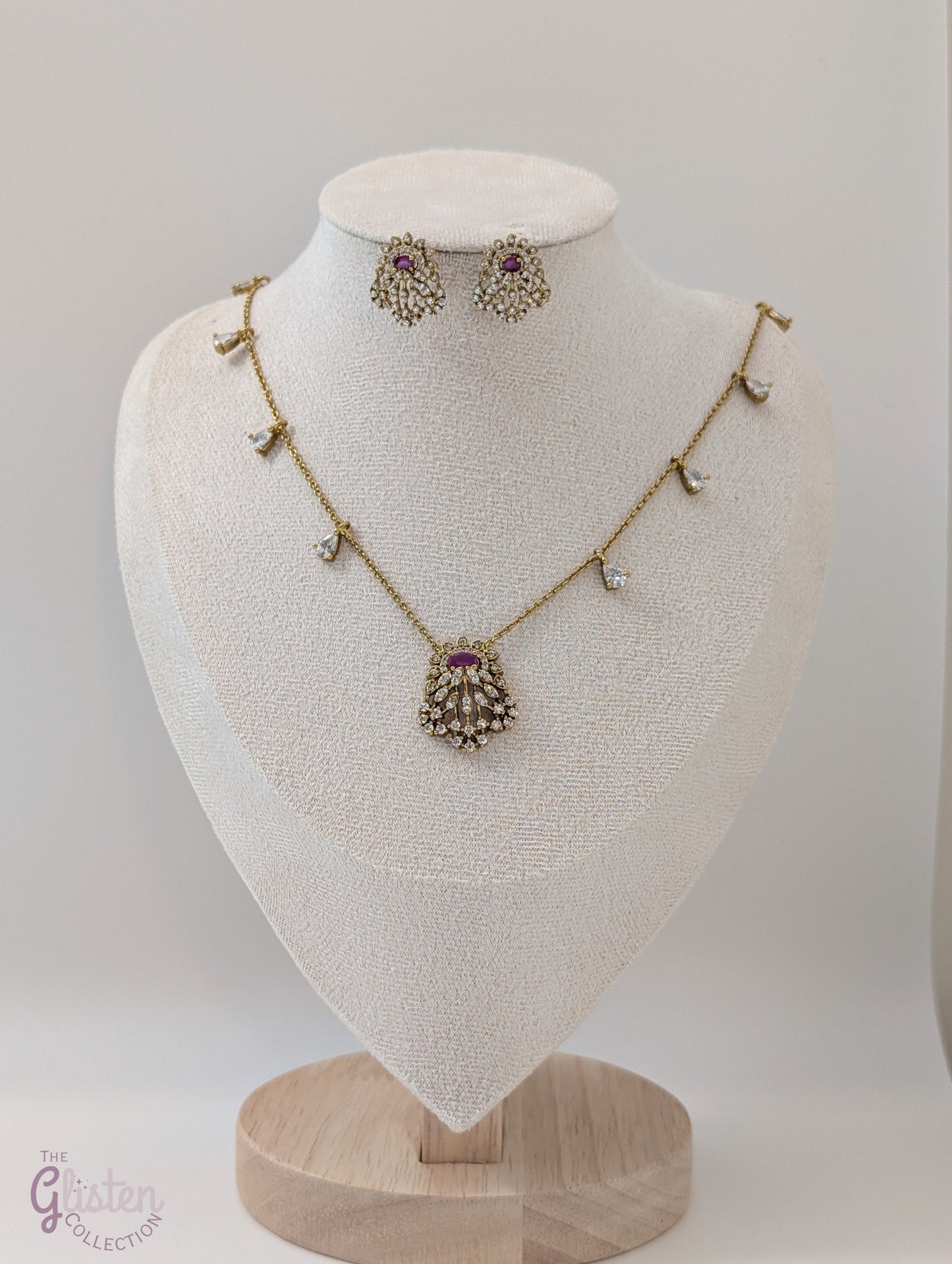 Gold-toned necklace and earrings set with red stone and CZ crystals, perfect for special occasions and everyday elegance, featuring delicate side stones and fine chain.