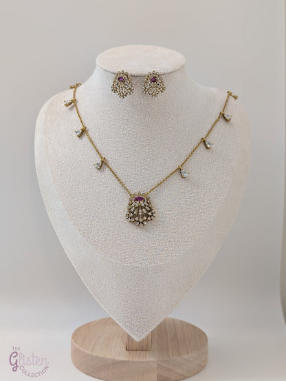 Gold-toned necklace and earrings set with red stone and CZ crystals, perfect for special occasions and everyday elegance, featuring delicate side stones and fine chain.