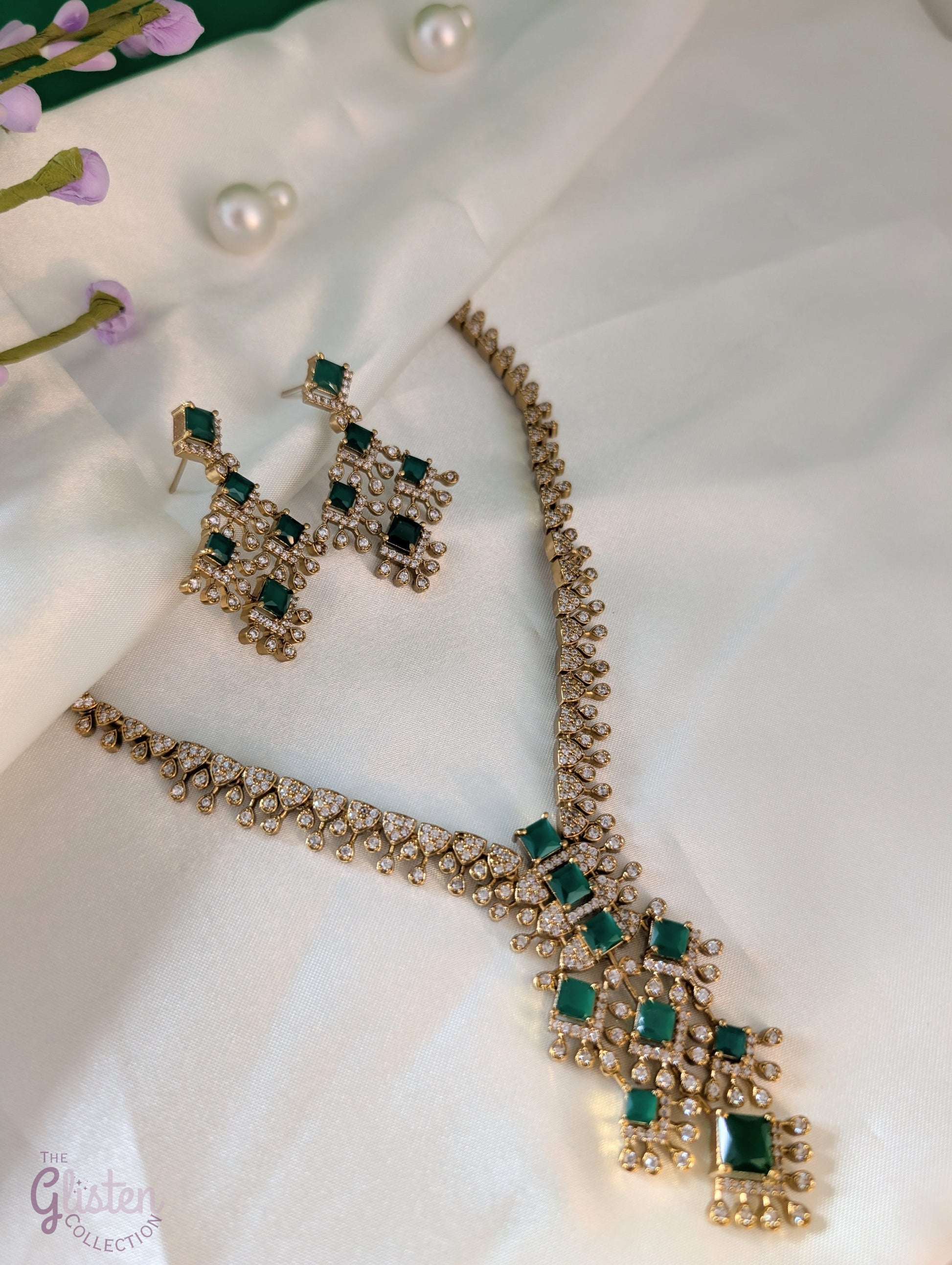 Necklace and earrings set with dangling emerald green stones in a geometric design, perfect for Indian wear, weddings, or cocktail parties.