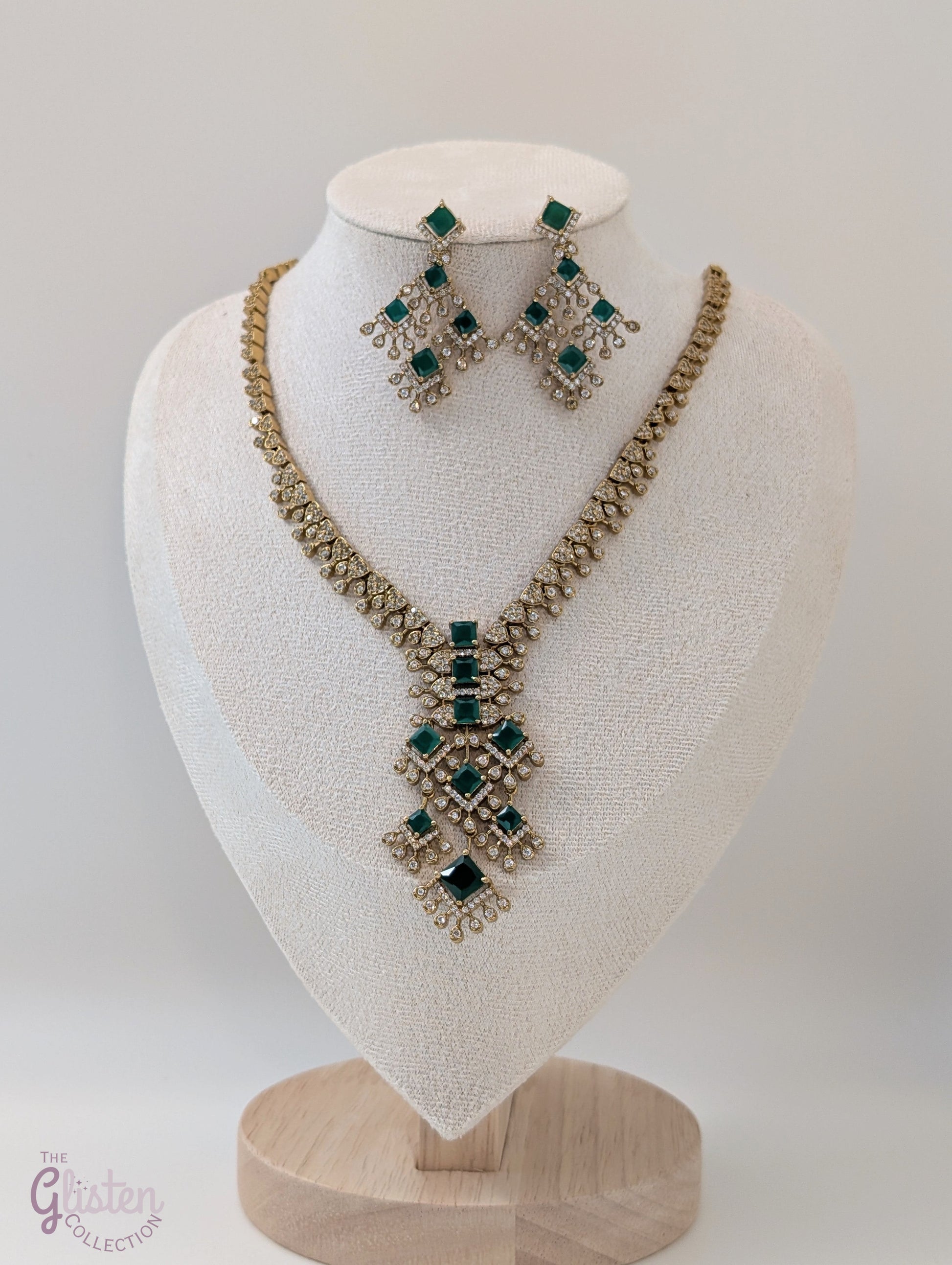 Necklace and earrings set with dangling emerald green stones in a geometric design, perfect for Indian wear, weddings, or cocktail parties.