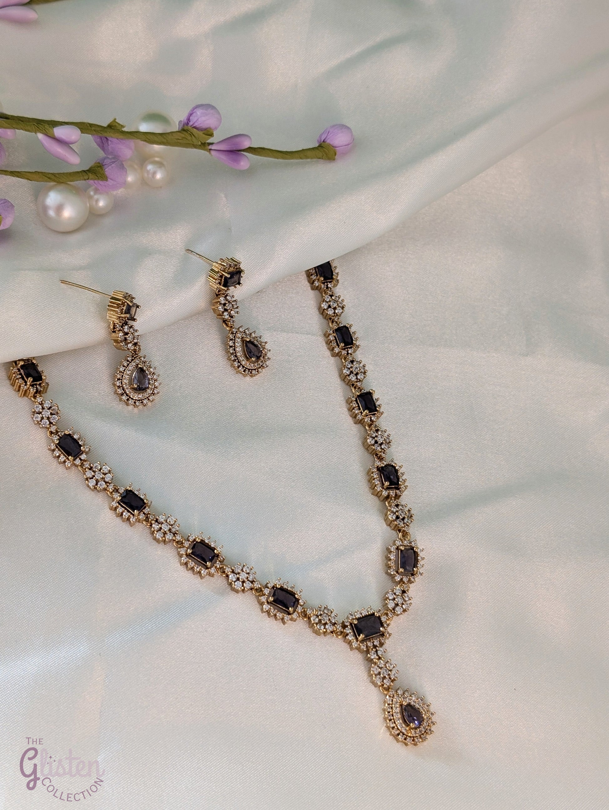 Gold-toned necklace and earrings set with deep purple drop stones, ideal for Indian attire, party dresses, and elegant everyday wear.