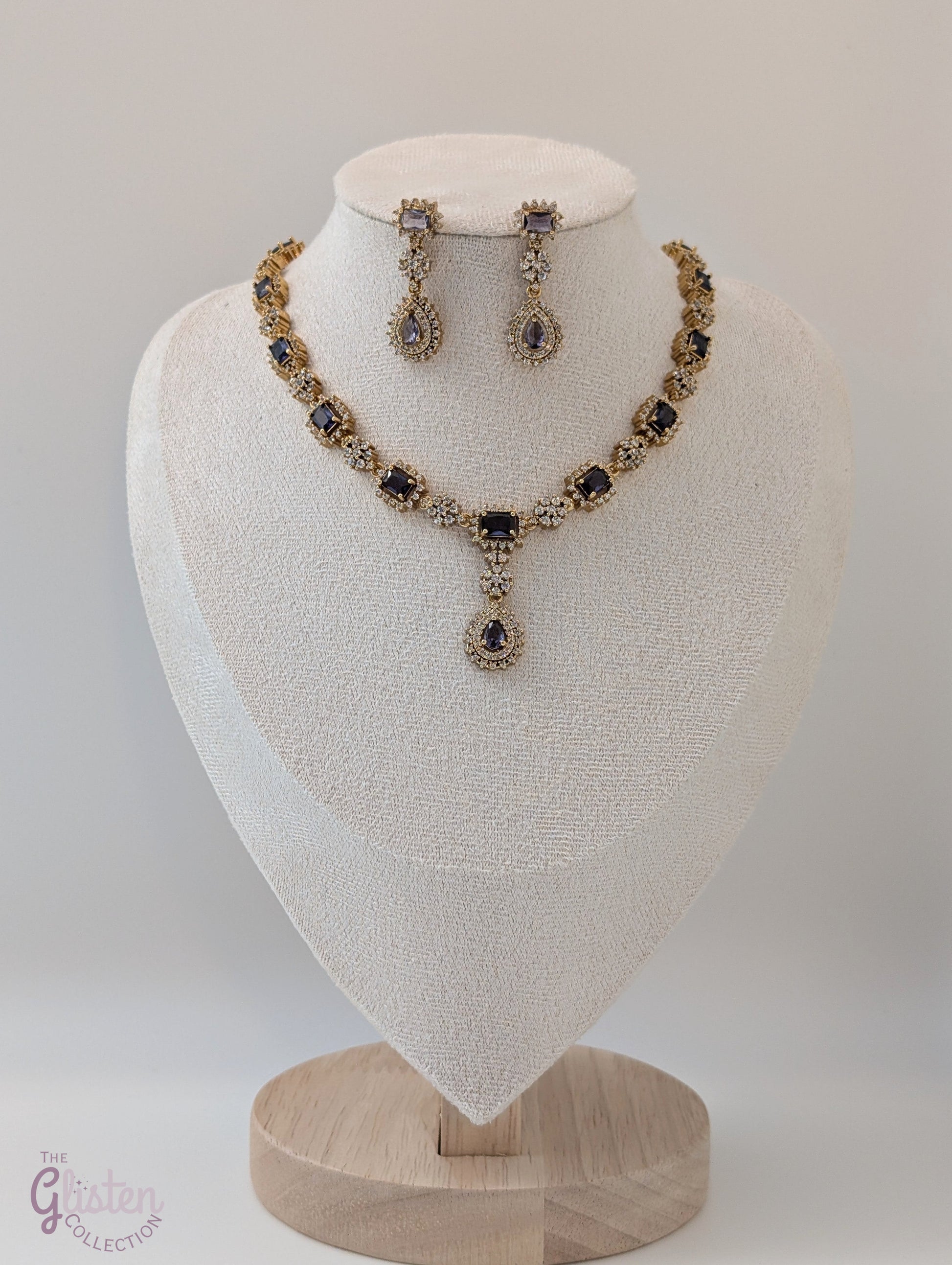 Gold-toned necklace and earrings set with deep purple drop stones, ideal for Indian attire, party dresses, and elegant everyday wear.
