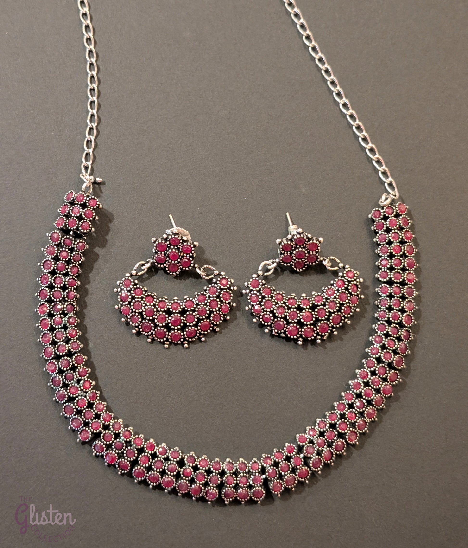 Oxidized silver necklace set with red stones and black finish, paired with crescent-shaped floral earrings — ideal for festive occasions and traditional Indian outfits.