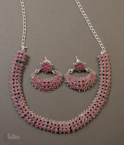 Oxidized silver necklace set with red stones and black finish, paired with crescent-shaped floral earrings — ideal for festive occasions and traditional Indian outfits.