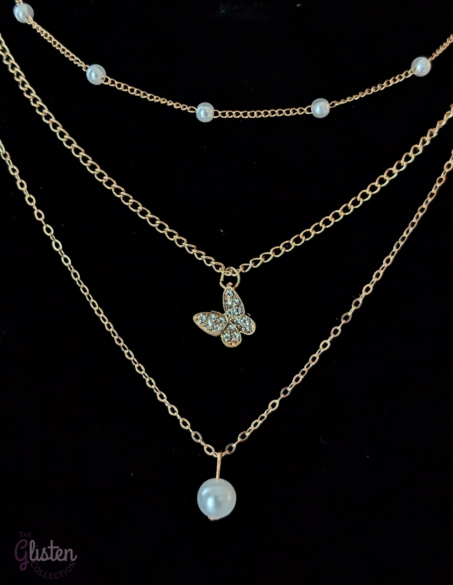 Three-layer gold necklace set with butterfly charm, pearl line, and single pearl pendant; can be worn individually or layered for a stylish statement.