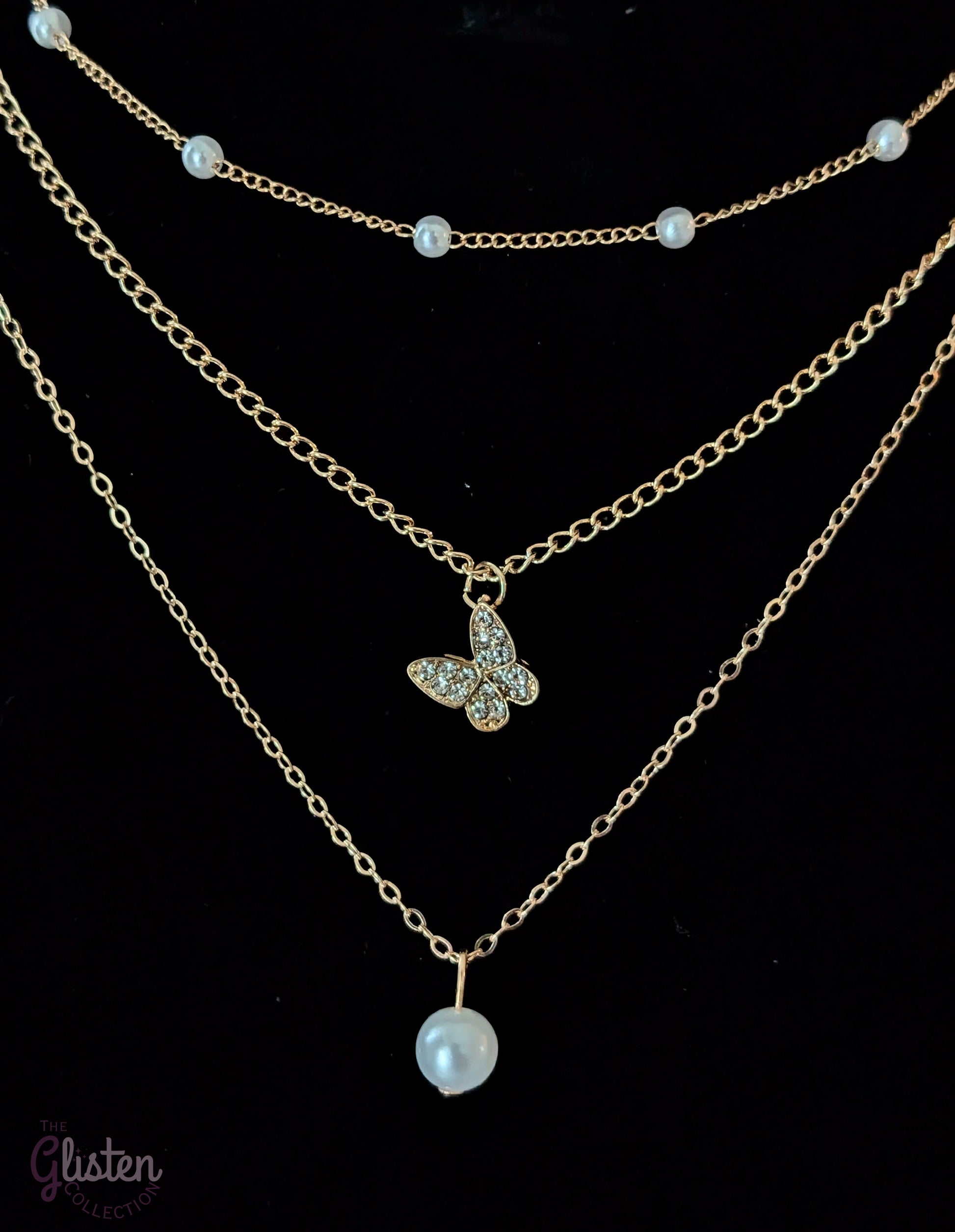Three-layer gold necklace set with butterfly charm, pearl line, and single pearl pendant; can be worn individually or layered for a stylish statement.