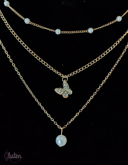 Three-layer gold necklace set with butterfly charm, pearl line, and single pearl pendant; can be worn individually or layered for a stylish statement.