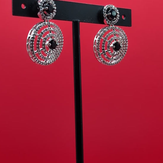 Gold-plated circular drop earrings with sparkling CZ stones and a bold black center stone from The Glisten Collection.