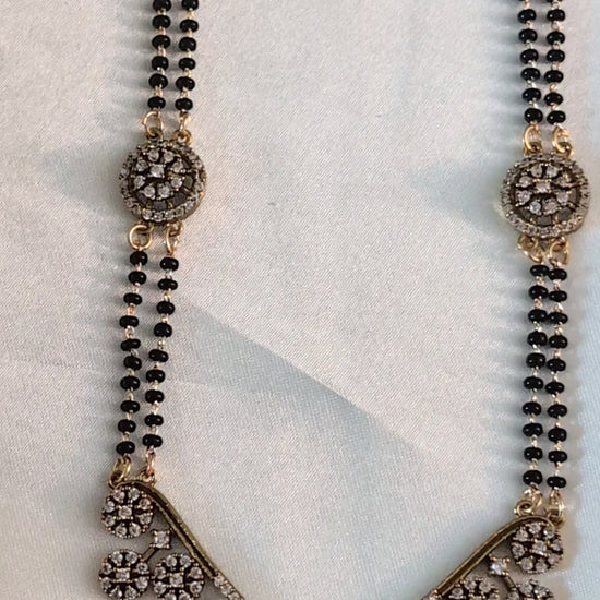 Long mangalsutra with black beads, V-shaped stone pendant, and round stone accents — ideal for modern traditional wear and daily elegance.